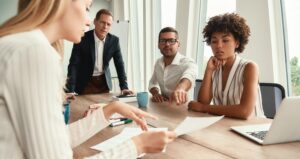 Reunião de negócios. Grupo de jovens empresários olhando documentos e discutindo algo enquanto estão sentados à mesa do escritório.